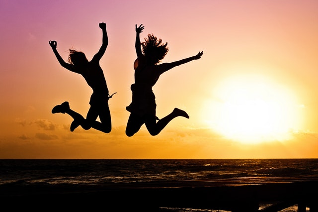 dvě skákající děvčata se západem slunce